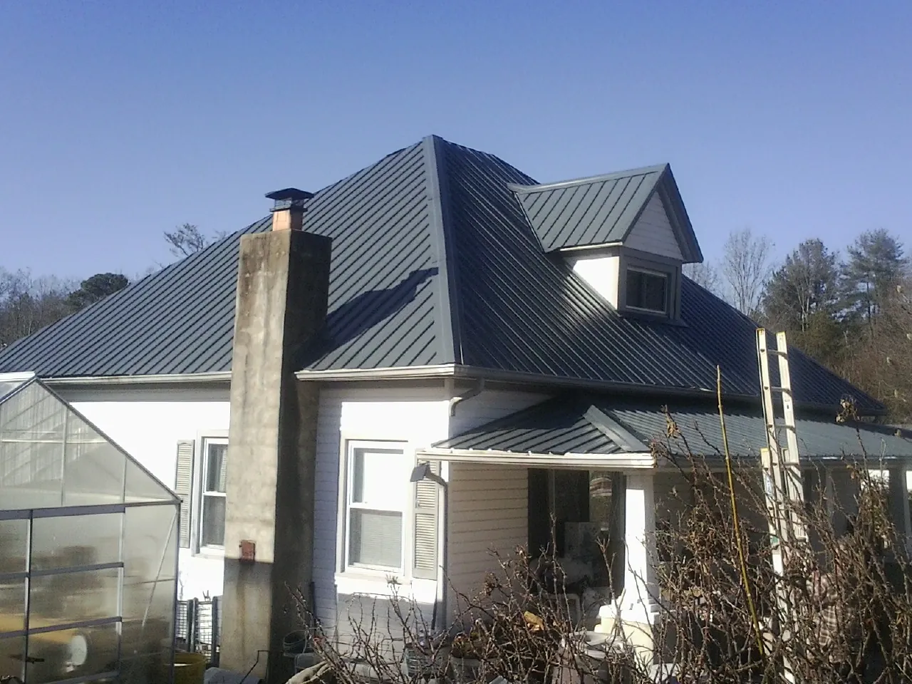 Dark blue standing seam metal roof on a white farmhouse with dormer — Slate & Tile Roof Repair by Roofing Brothers in Arapahoe