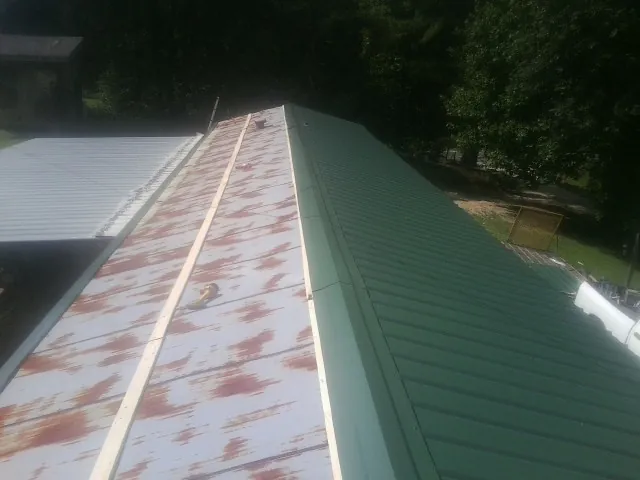 Old rusted panels beside newly installed green metal roofing — Wind Damage Roof Repair by Roofing Brothers in Arapahoe