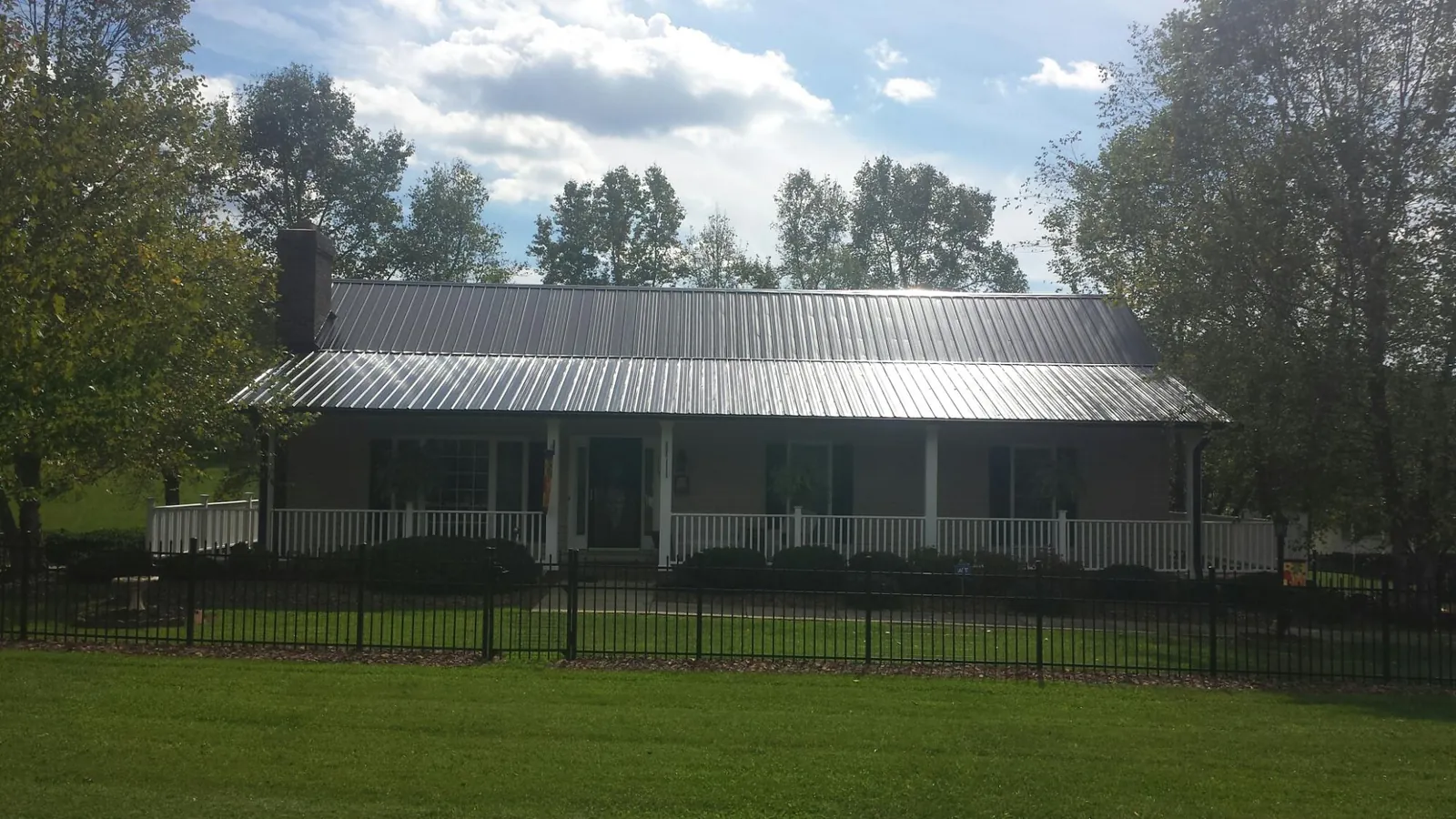 Gray metal roof on a brick ranch with a full width front porch — Gutter Guard Installation work by our crew in Arapahoe