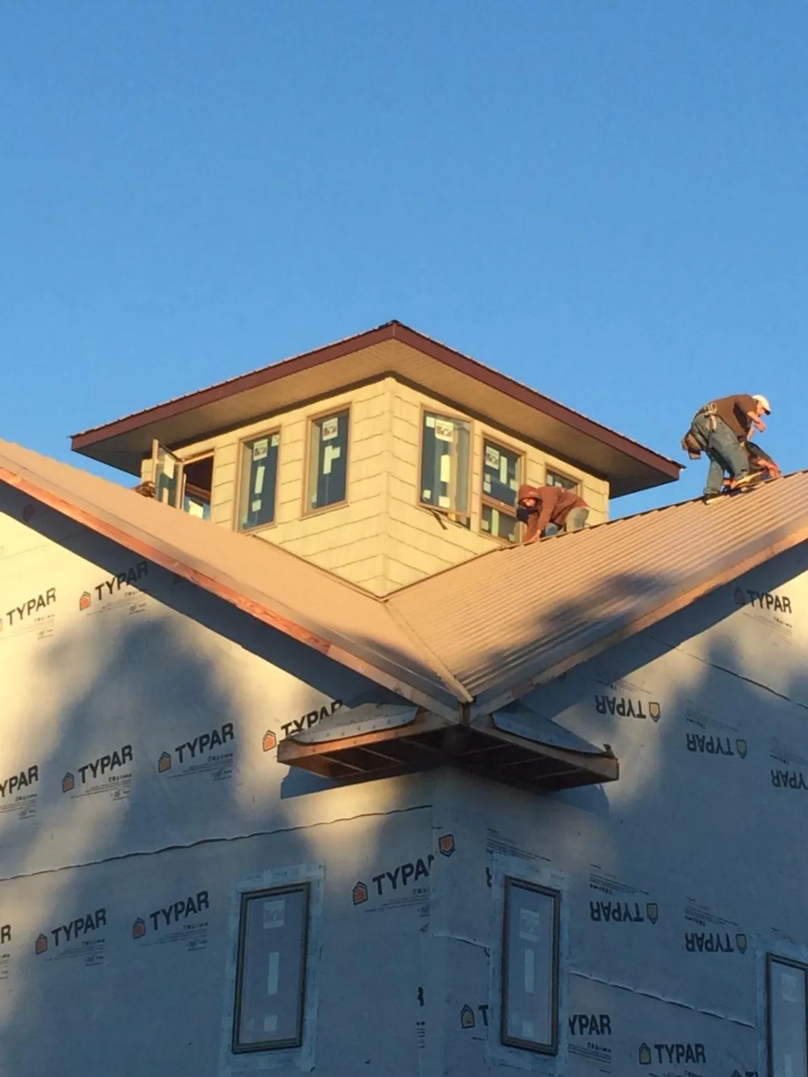 Roofers working around a rooftop cupola on a new metal roof at sunset — Roof Waterproofing in Arapahoe by Roofing Brothers